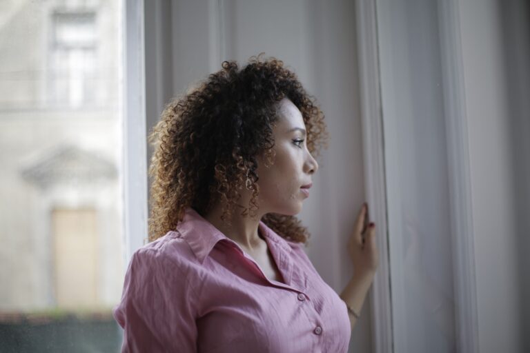 A woman sitting quietly by a window in warm natural light.