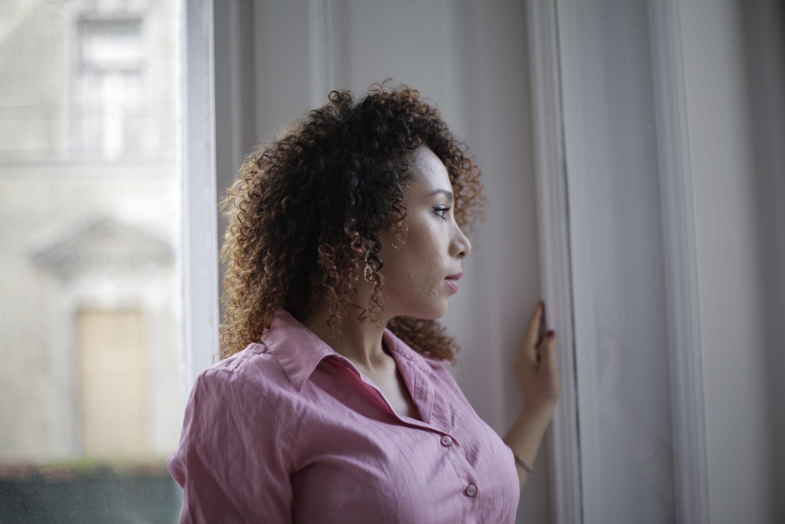 A woman sitting quietly by a window in warm natural light.
